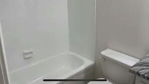 Een badkamer met een bad, toilet en een douchehoek.