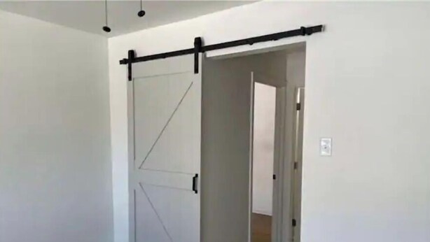 Une pièce dotée d’une porte coulissante de style grange et d’un couloir menant à une autre pièce.