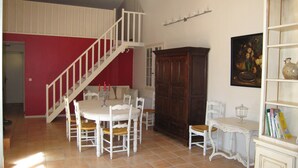 Zona pranzo con tavolo rotondo, sedie bianche, una scala e un mobile in legno.