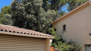 Un edificio con un portone garage chiuso, una scala che conduce al secondo piano e un vialetto sterrato.