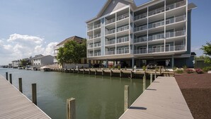 Un hotel de varios pisos con balcones, un embarcadero y un puerto deportivo al fondo.