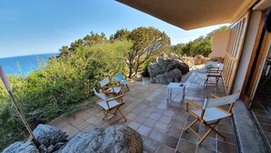 Eine Terrasse im Freien mit Sitzgelegenheiten, einem Tisch und Blick auf das Meer.
