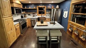 A modern kitchen with wooden cabinets, stainless steel appliances, and a central island with stools.