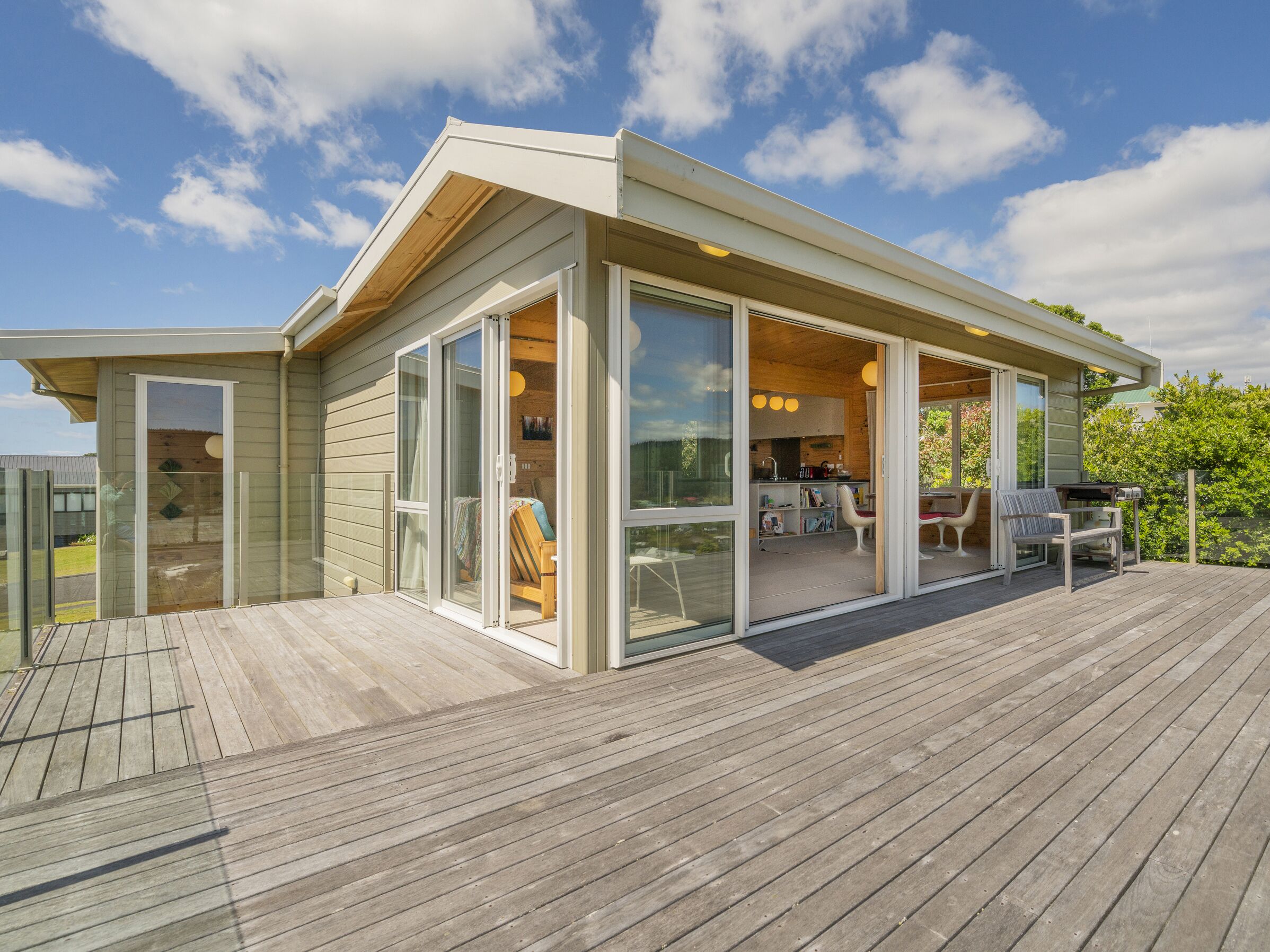 Una casa moderna con terraza, grandes puertas correderas de vidrio que dan a una sala de estar y una cocina a la vista.