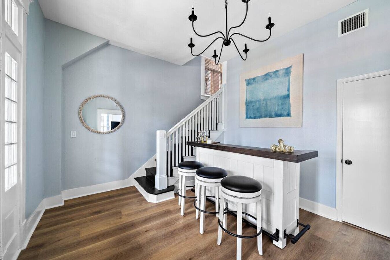 A staircase with white railings and black steps, leading to a landing with a bar and stools.