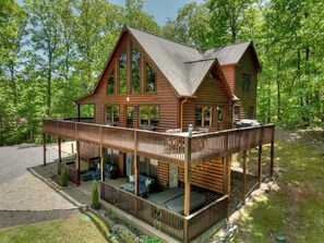 A two-story log cabin with a deck and outdoor seating area.
