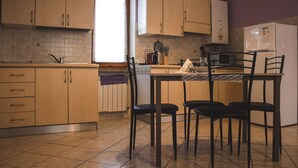 Une cuisine avec des meubles de rangement en bois, un pare-feu en carreaux, une fenêtre et une table à manger avec des chaises.