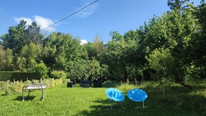 Un espace extérieur avec un banc en métal et deux chaises en plastique bleues.