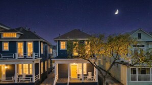 A row of two-story houses with a porch and steps leading to the front door, under a starry night sky. - Charming Home Near Downtown with Pool & Fire Pit (Galveston)