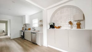 A modern kitchen with white cabinetry, a central island, and a large arched window.