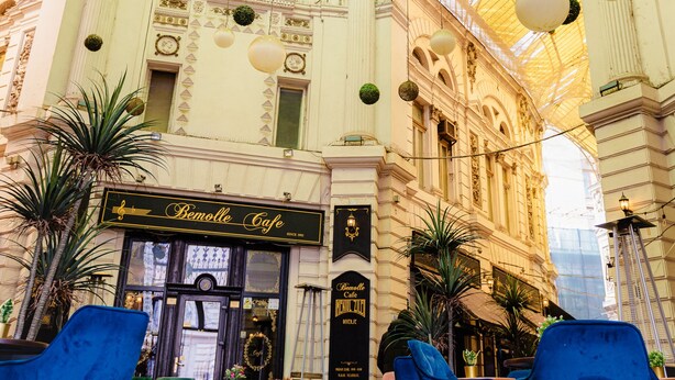 Un interior ornamentat amb bressols, una cafeteria anomenada 'Bemoiselle Café' i cadires blaves.