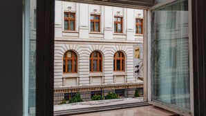 Una habitació amb un finestra gran que fa a un edifici amb diverses finestres i un balcó.