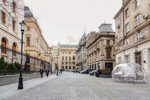 Eine gepflasterte Straße, gesäumt von historischen Gebäuden, einer transparenten Kuppelstruktur und einigen Fußgängern.