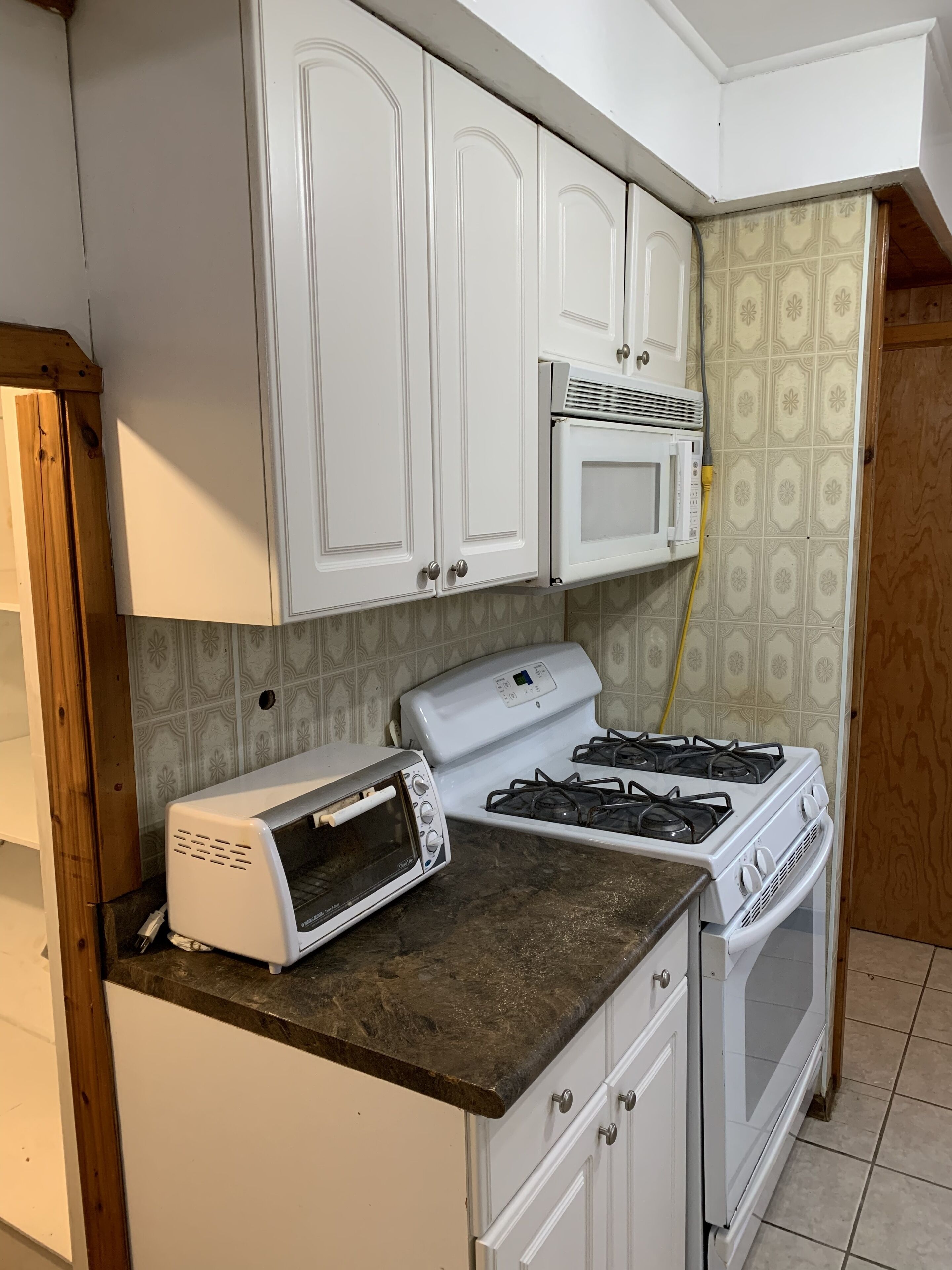 A kitchen with white cabinets, a microwave, a stove, and a toaster.