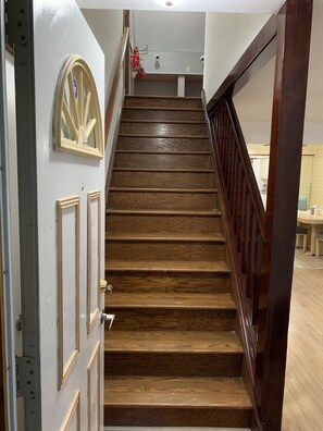 Staircase leads to an upper floor with a door and handrail.