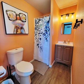 Ein Badezimmer mit Toilette, Waschbecken, einer Duschkabine und einem gerahmten Bild an der Wand.