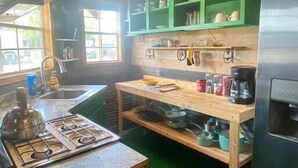 Une cuisine avec des meubles de couleur verte, un plan de travail en bois et un motif de tournesol sur le sol.