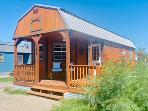 A wooden cabin with a porch, a small window, and a metal roof.