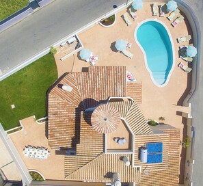 En pool på taget med liggestole, parasoller og jacuzzi.