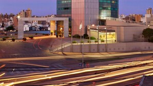 A tall, modern building with a curved top and a glass facade, surrounded by a well-lit urban area. - Quinto Centenario Hotel (Córdoba)