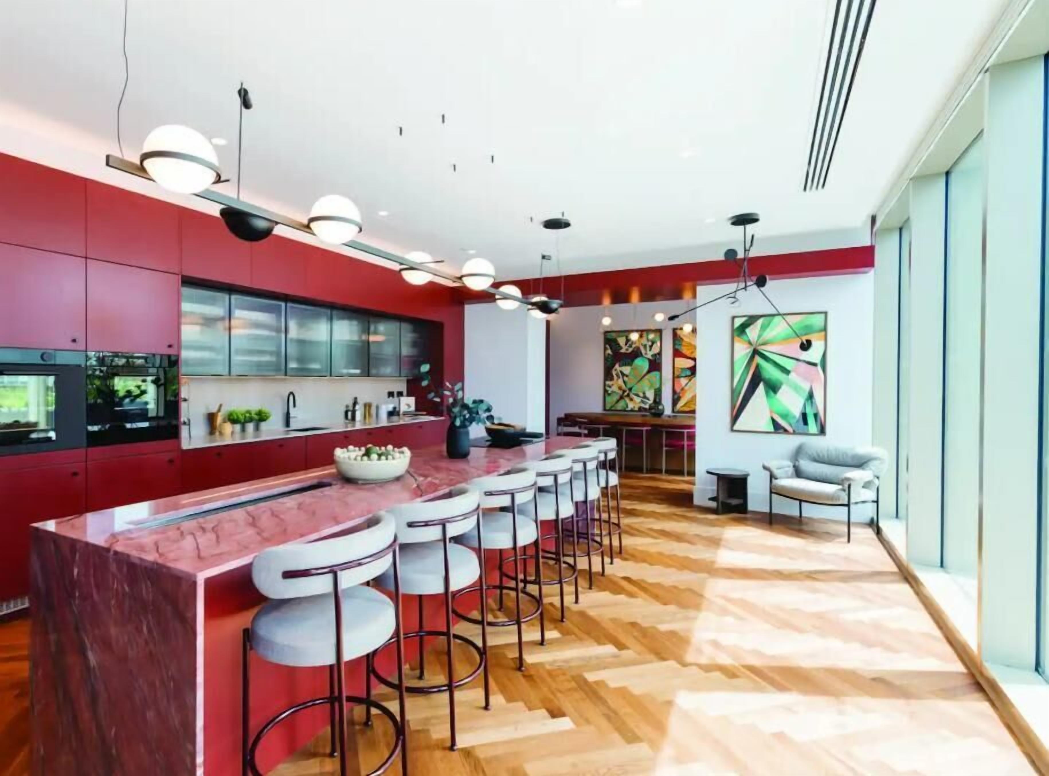 A modern kitchen with a red theme, a bar area with stools, and a dining area with a view.