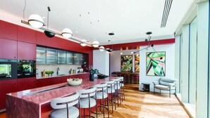 Een moderne keuken met een rood thema, een bar met krukken en een eethoek met uitzicht.