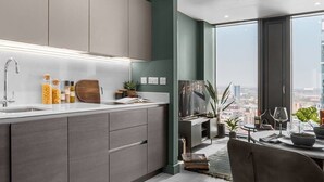 A modern kitchen with a large window, a dining area with a view, and a cityscape visible through the window. - The Mercian 1 XVIII- 1BDR |STUNNING CITY SKYLINE VIEWS! 24-Hour GYM | CINEMA room (West Midlands)