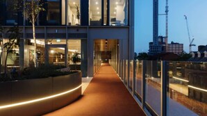 A modern building with a glass facade, a curved walkway, and a view of the city skyline. - The Mercian 2 I - 1BDR |STUNNING CITY SKYLINE VIEWS! 24-Hour GYM | CINEMA room (West Midlands)