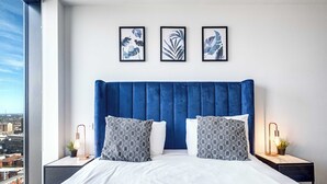 Ein modernes Hotelzimmer mit einem großen Bett, zwei Nachttischen und Blick auf die Stadt.