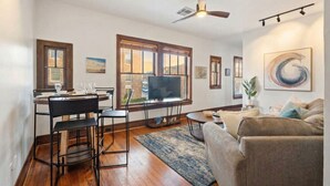 Una sala de estar con comedor, un ventilador de techo y un televisor sobre un mueble.