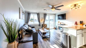 A modern living room with a sofa, coffee table, and a dining area with a kitchen counter.