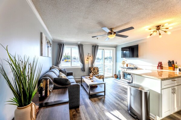 A modern living room with a sofa, coffee table, and a dining area with a kitchen counter.