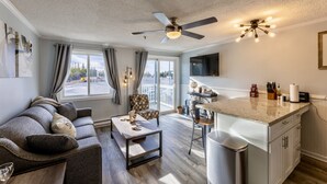 A modern living room with a sofa, a coffee table, and a dining area with a kitchen counter.
