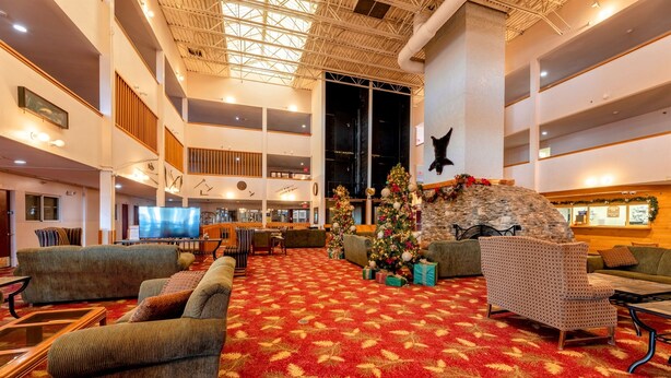 A spacious lobby with a red carpet, multiple seating areas, a Christmas tree, and a stone fireplace.