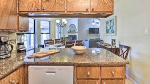 A kitchen with wooden cabinets, granite countertops, a dishwasher, and a dining area with chairs and a table. - Granbury Home w/ Lake Granbury Access + Dock! (Granbury)