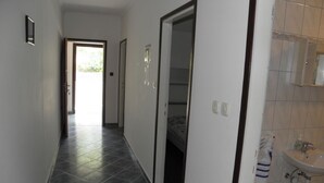 A hallway with a tiled floor, a door leading to a bedroom, and a bathroom with a sink and toilet.