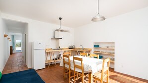 A compact kitchen with a dining area, white walls, and wooden furniture. - Quiet and bright village house (Silves)