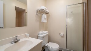 A bathroom with a sink, toilet, and a glass shower enclosure. - Nevada Flats Hotel (Colorado Springs)
