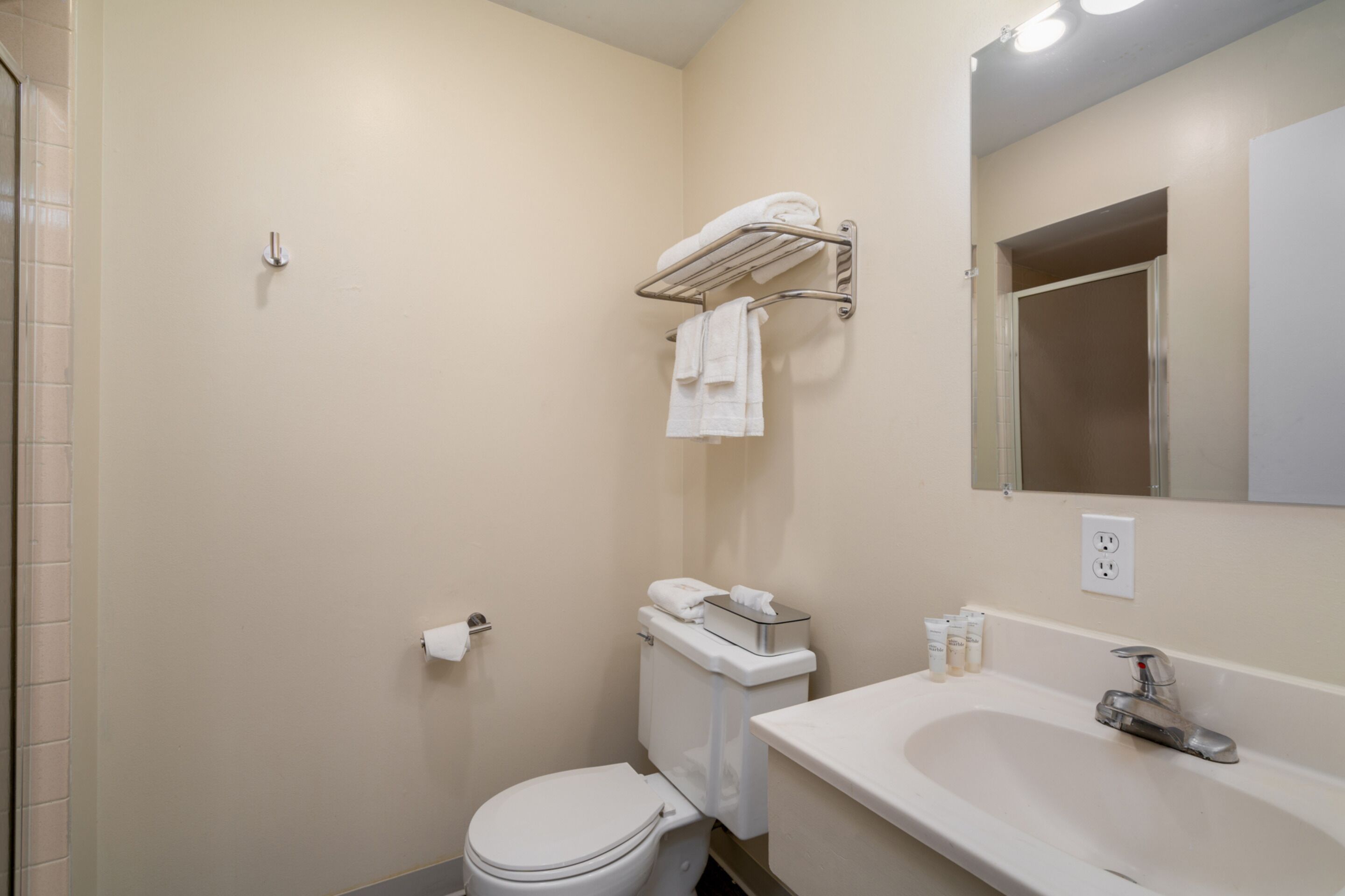Un baño con inodoro, lavamanos y toallero.