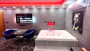 A modern bathroom with a large bathtub, a wall-mounted TV, and a painting. - Levent Palace Hotel (Istanbul)