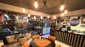A modern cafe with a round table, orange chairs, and a coffee bar. - Levent Palace Hotel (Istanbul)