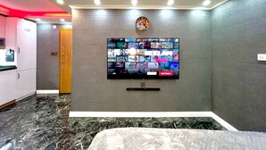 A modern hotel lobby with a large TV screen displaying various channels, a marble floor, and a red-lit ceiling. - Levent Palace Hotel (Istanbul)