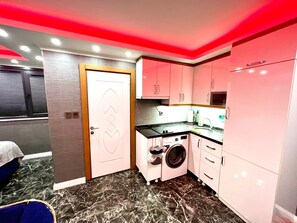 A compact kitchen with a washing machine, a microwave, and a sink. - Levent Palace Hotel (Istanbul)