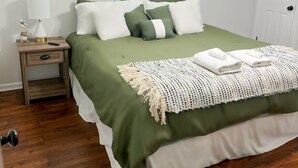 A bedroom with a bed, a nightstand, a lamp, a window, and a ceiling fan. - Bristow Bungalow (Tupelo)
