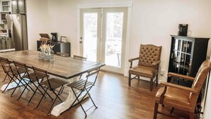 A dining area with a wooden table and chairs, a black cabinet, and a view through glass doors to the outside. - Bristow Bungalow (Tupelo)