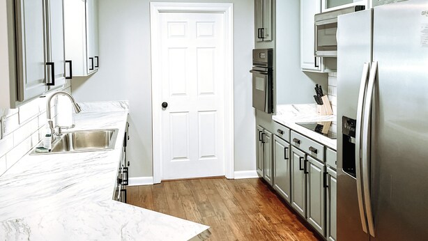 A modern kitchen with a marble countertop, stainless steel appliances, and wooden flooring. - Bristow Bungalow (Tupelo)