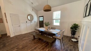 Un espace repas comprenant une table en bois, un banc et un luminaire suspendu.