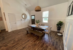 Enjoy meals at the dining table with benches, surrounded by natural light and a potted plant.