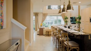 Uma cozinha moderna com uma mesa de jantar comprida, luminárias pendentes e vista para o exterior.