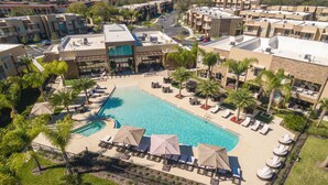 Eine Luftaufnahme eines Resorts mit einem großen Schwimmbecken, mehreren Gebäuden und Palmen.